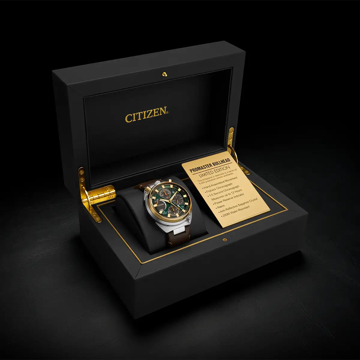 A Citizen watch presented in an open black branded box with gold trim, alongside a small card, on a dark studio background.