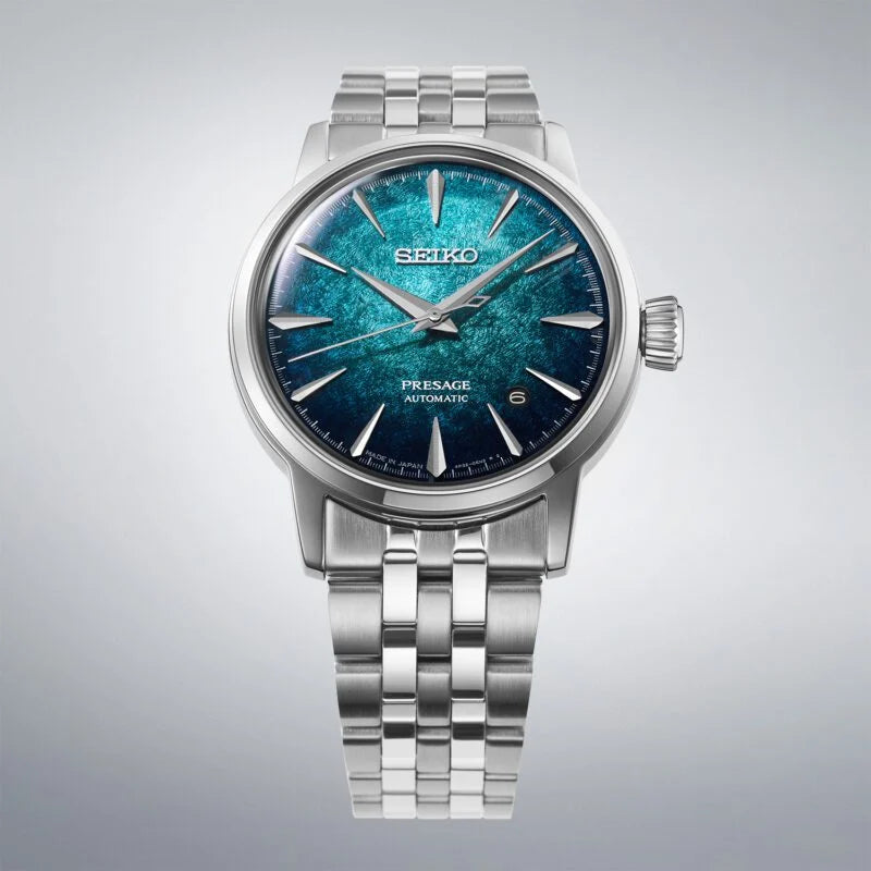 A Seiko Pressge Automatic watch with a silver stainless steel case and link bracelet, featuring a textured blue and teal dial.
