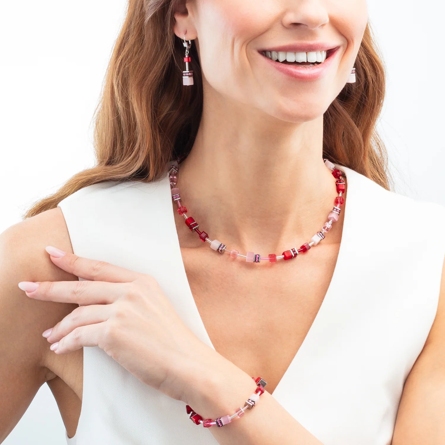 Woman wearing a red and white beaded necklace and bracelet on a white background