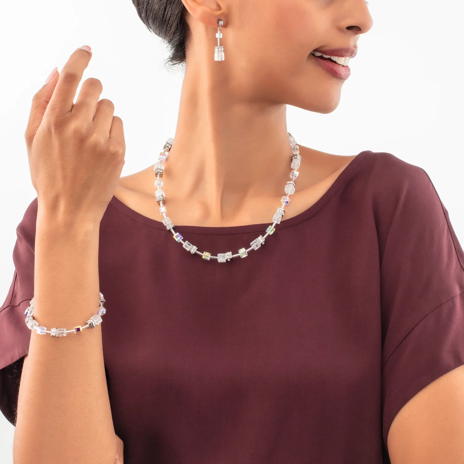 Woman wearing a necklace and bracelet with a plain background