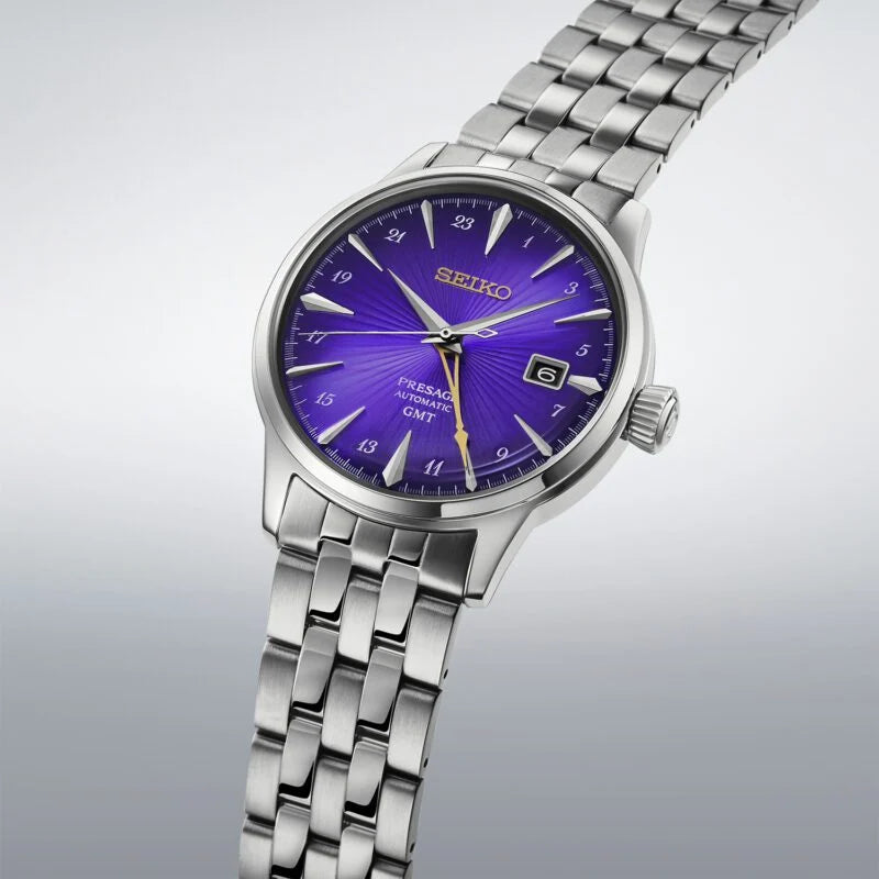 A Seiko women's wristwatch with a silver stainless steel link bracelet and a vibrant purple sunburst dial, shown on a light gray gradient background.