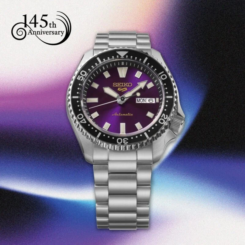 A Seiko automatic wristwatch with a silver stainless steel case and link bracelet, featuring a purple dial and a black rotating bezel. The watch is presented on a vibrant purple, blue, and black gradient background with a '145th Anniversary' logo in the top-left corner.