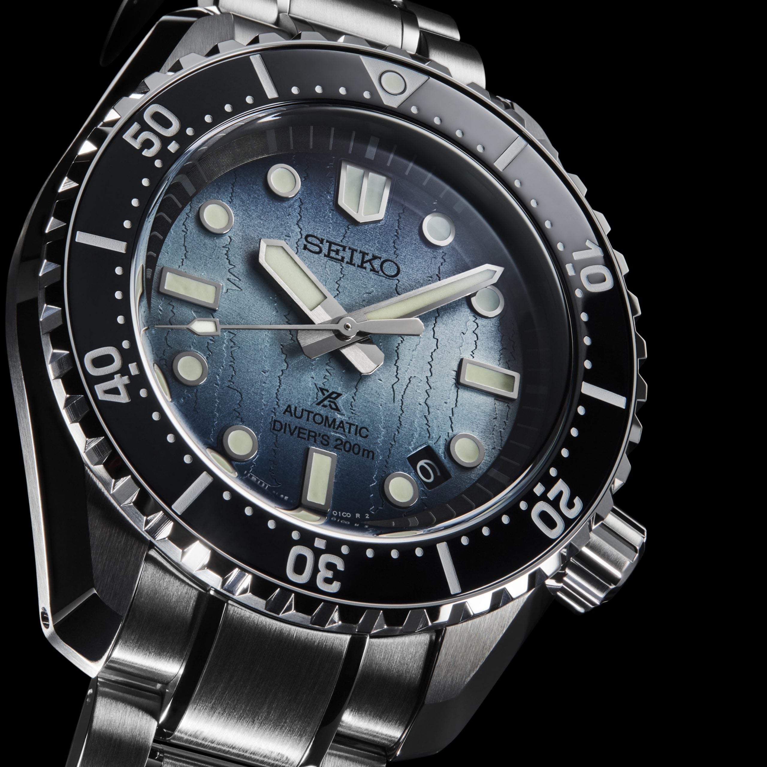 Seiko watch with blue dial and silver metal strap on a black background